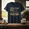 Navy t-shirt with distressed text "I STILL PLAY WITH TRACTORS" and a vintage green tractor graphic inside a circle border