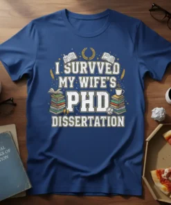 I Survived My Wife's PhD Dissertation text on a blue t-shirt, featuring stacks of books and graduation laurels