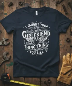 I TAUGHT YOUR GIRLFRIEND THAT THING THING YOU LIKE text design on a dark navy t-shirt, featuring heart and wings