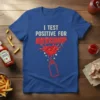 Blue t-shirt with white and red text that reads "I TEST POSITIVE FOR KETCHUP" and a ketchup splash graphic