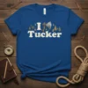 Blue t-shirt with "I Tucker" text, axe graphic, compass, and pine trees