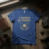 Blue t-shirt with gold text "i wanna go home." and a house graphic within a wreath