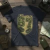 I WAS NOW I'M 67 military camouflage design on a navy blue t-shirt, featuring shield and hands graphic