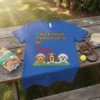 Blue t-shirt with text "I WAS TOLD THERE WOULD BE Dogs" and illustration of three cute dogs peeking over grass