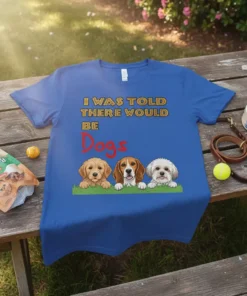 Blue t-shirt with text "I WAS TOLD THERE WOULD BE Dogs" and illustration of three cute dogs peeking over grass