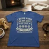 I WORK HARD SO MY DOG CAN HAVE A BETTER LIFE quote with paw prints graphic on a blue t-shirt