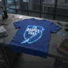 T-shirt with "I'D BIOPSY THAT" text inside a neon blue shield graphic, featuring a medical scalpel