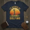 I'D RATHER BE GOLFING text with a golfer swinging at sunset graphic on a navy t-shirt