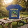 I'd Rather Be Mowing text with a green riding lawn mower graphic on a blue t-shirt