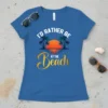 I'd Rather Be At The Beach text with palm trees and sunset graphic on a blue t-shirt