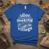 White text 'idiot seeking village' with a charming village graphic on a royal blue t-shirt