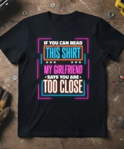 Black t-shirt with neon-style text reading "IF YOU CAN READ THIS SHIRT MY GIRLFRIEND SAYS YOU ARE TOO CLOSE" in