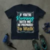 T-shirt with the quote "IF YOU'RE RUNNING WITH ME BE PREPARED TO WALK" in turquoise and gold typography, featuring futuristic