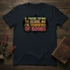 Dark t-shirt with the text "IF YOU'RE TRYING TO SCARE ME I'M TERRIFIED OF BOOBS" in distressed yellow and pink