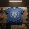 I'll Be In The Barn text with barn graphic and wheat wreath on a blue t-shirt