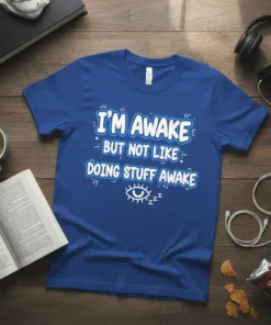 Blue t-shirt with white and blue text that reads "I'M AWAKE BUT NOT LIKE DOING STUFF AWAKE" and a sleepy