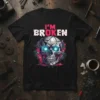 Black t-shirt with bold pink and white "I'M BROKEN" text above a detailed, glowing-eyed mechanical skull design