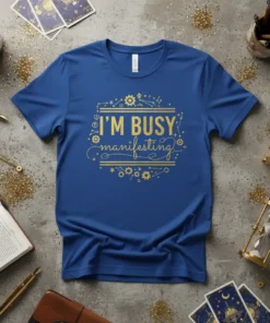 Blue t-shirt with gold text "I'M BUSY manifesting" and celestial graphics, ideal for manifestation and law of attraction enthusiasts