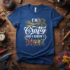I'm Crafty And I Know It quote on a blue t-shirt with golden scissors, spools of thread, and sewing needles