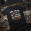 Black t-shirt with white and orange text that reads "I'm Here Because You Broke Something" and features wrench and gear