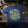 Blue t-shirt with yellow and white text "I'm Here Because You Broke Something" surrounded by mechanical tools and parts