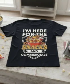 Black t-shirt with white text "I'M HERE FOR THE SNACKS AND COMMERCIALS" above a graphic of a bowl of snacks