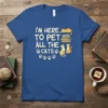 I'm Here To Pet All The Cats quote with cute cat illustrations and paw prints on a blue t-shirt