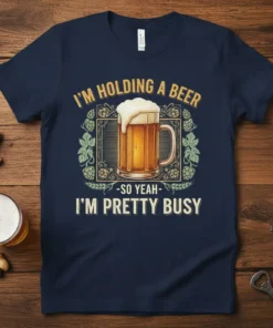 Navy blue t-shirt featuring the quote "I'm Holding A Beer - So Yeah - I'm Pretty Busy" with a graphic