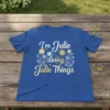 T-shirt with the quote "I'm Julie doing Julie Things" in playful typography, surrounded by floral elements and a smiling sun