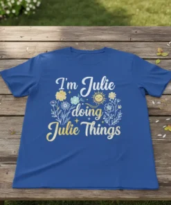 T-shirt with the quote "I'm Julie doing Julie Things" in playful typography, surrounded by floral elements and a smiling sun