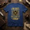I'm Just Here So I Don't Get Fined quote t-shirt featuring a gargoyle shield graphic and distressed gold lettering