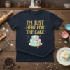 I'm Just Here For The Cake quote with a colorful tiered cake graphic on a navy blue t-shirt