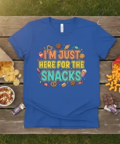 I'm Just Here For The Snacks quote on a blue t-shirt, surrounded by colorful illustrations of cookies, candy, and pretzels