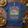 I'm Just Here For The Tacos shirt featuring a colorful sugar skull and retro sunset graphic, with skeleton figures