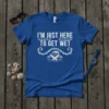 Blue t-shirt with white text "I'm Just Here To Get Wet" and a graphic of a surfboard in waves