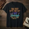 Black t-shirt with the quote "I'm Just Wtf-ing My Way Through Life" in colorful, distressed typography, featuring steampunk-inspired gears and