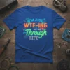 I'm Just WTF-ing My Way Through LIFE text design with glitch art and neon city background on a blue t-shirt