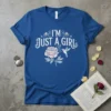 Blue t-shirt with "I'm Just A Girl" text, a pink peony flower, and a hummingbird graphic