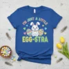 I'm Just A Little Egg-stra text with a cute Easter bunny and colorful eggs graphic on a blue t-shirt