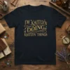 T-shirt with "I'm Kaitlyn Doing Kaitlyn Things" in decorative gold and teal lettering, featuring stars and swirls
