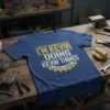 Blue t-shirt with yellow and white text reading "I'M KEVIN DOING KEVIN THINGS KEVIN THINGS" in a workshop setting
