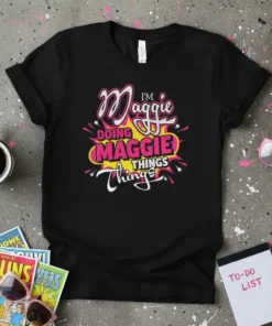 Black t-shirt with colorful text reading "I'M Maggie DOING MAGGIE THINGS Things" in a playful, vibrant design