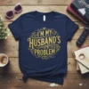 Navy blue t-shirt with gold glitter text "I'm My Husband's Problem" in a decorative circular design