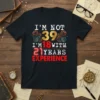 I'm Not 39 I'm 18 With 21 Years Experience quote on a black t-shirt, featuring vintage gears and bold typography