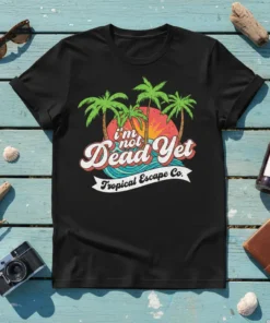 Black t-shirt with "I'm Not Dead Yet Tropical Escape" text, palm trees, and sunset graphic