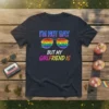 I'm Not Gay But My Girlfriend Is text with rainbow cracked sunglasses graphic on a black t-shirt, pride design
