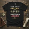 Black t-shirt with "I'm Not Getting Old I'm Becoming A Legend" quote in vintage style font, featuring compass graphic and
