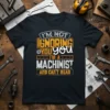 Black t-shirt with white, orange, and grey text that reads "I'M NOT IGNORING YOU YOU I'M A MACHINIST AND CAN'T