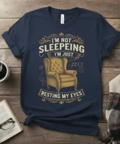 Navy t-shirt with vintage-style text "I'm Not Sleepeing I'm Just Resting My Eyes" and an illustration of a tufted armchair