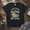 Funny "I'm Not Sleeping I'm Just Resting My Eyes" quote on a black t-shirt, featuring a person napping on a